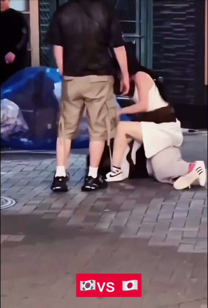On the streets of Dotonbori shopping district in Osaka, Japan, Japanese and Korean girls had a scuffle over a quarrel. The Korean girl in white clothes and short skirts had the upper hand, and she pinned the Japanese girl in black clothes and white pants to the ground.